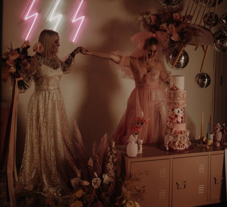 pink dress for wedding with alternative cake table decorated with neon signs and glitter balls