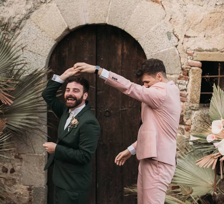 Groom in Pink Wedding Suit Twirling His Partner in a Green Wedding Suit