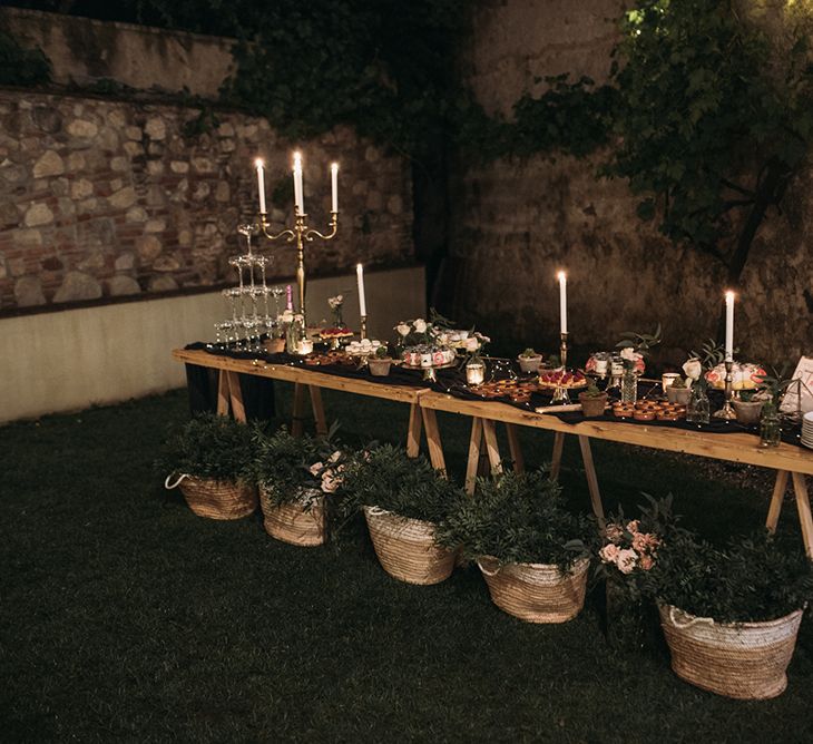 Dessert Table with Food Platters, Silver Candelabra and Woven Baskets Full of Foliage