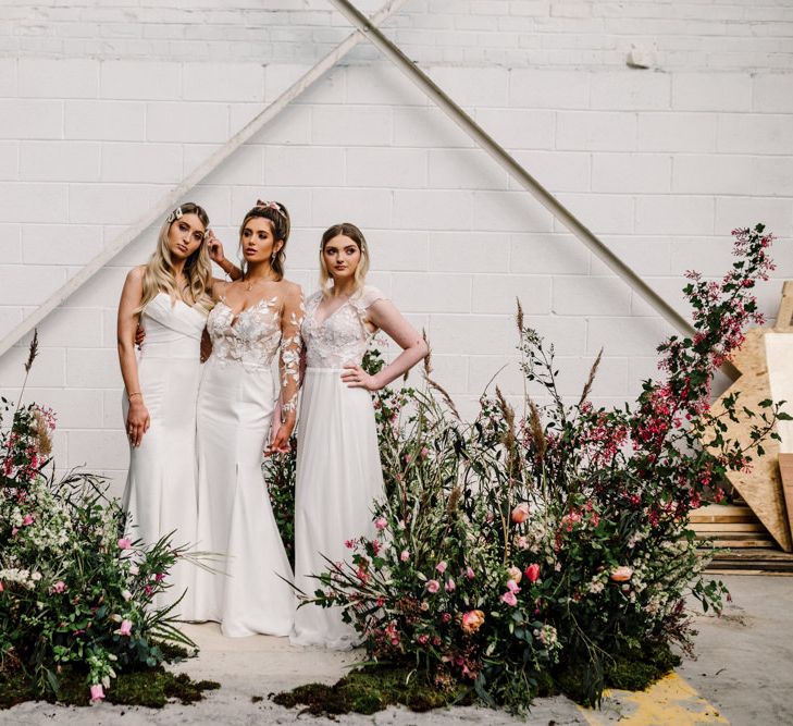 Industrial Wedding Venue with Three Brides Standing by Deep Pink and Foliage Floral Arrangements