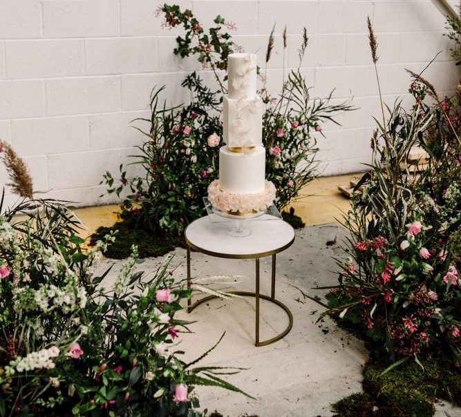 Wedding Cake in Marble Top Nest Table Surrounded by Deep Pink and Foliage Floral Arrangements