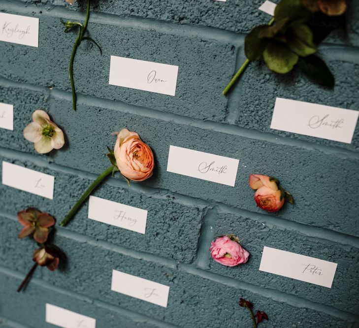 Flowers Stems and Name Place Cards Pinned to a Wall