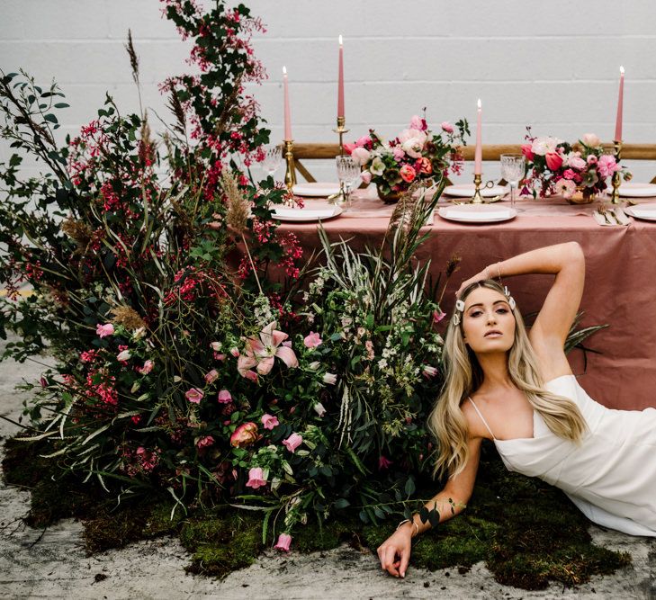 Bride in Fitted Strappy Wedding Dress Next to a Beautiful Light Pink and Dark Pink Tablescape