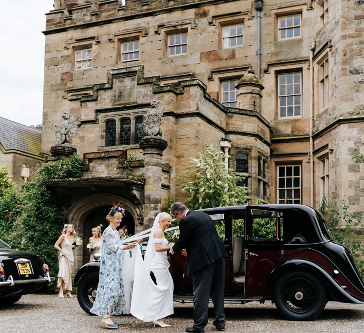 Bride in Savannah Miller wedding dress getting into a vintage wedding car