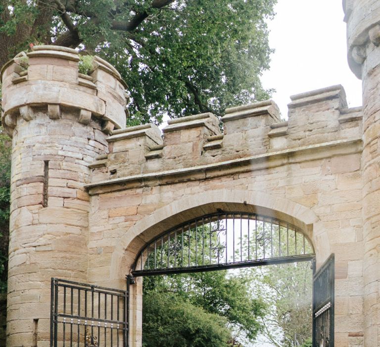 Bride's car passes under fortified gates at Hawarden Castle in Wales, UK