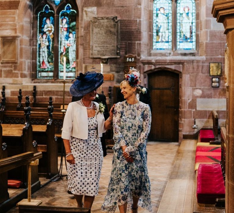 Bride and groom's mother look at each other and exchange a moment of happiness as they walk towards the signing of the register