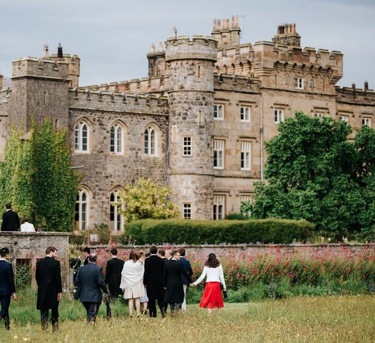 Guests and family walk across the lawn towards Hawarden Castle for the drinks reception