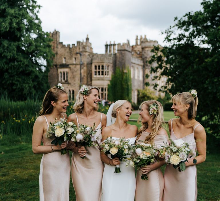 Smiling photograph of bridesmaids and bride holding bouquets with Hawarden Castle in the background