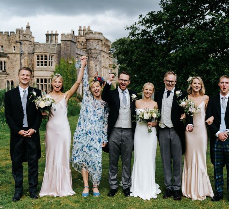 Posed family photograph of bride, groom and bride's family with Hawarden Castle in the background