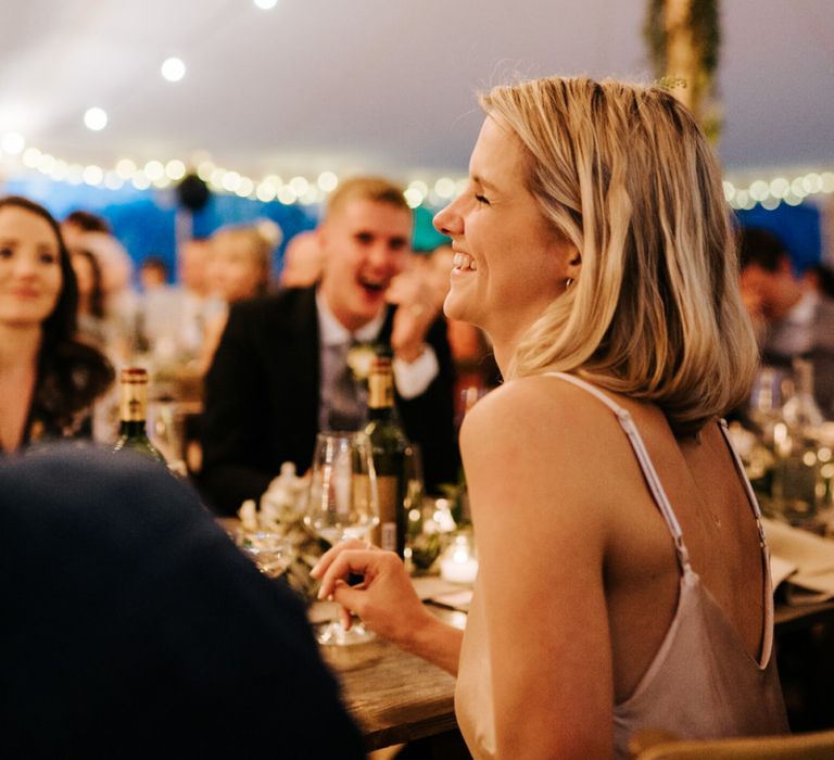 Sister of the bride smiles graciously during groom's speech