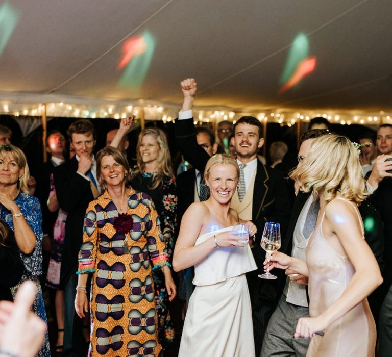 Bride smiles in front of dancefloor as she is wearing her second outfit of the day