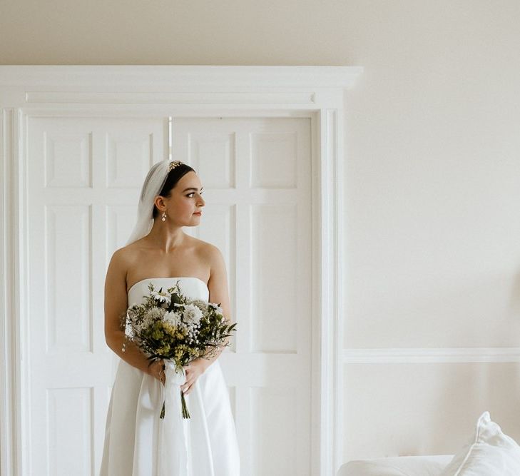 Bride Holds Bouquet In Front Of Strapless Wedding Dress