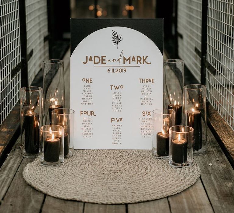 Black and Gold Seating Chart with Contemporary Design and Gold Font Surrounded by Candles