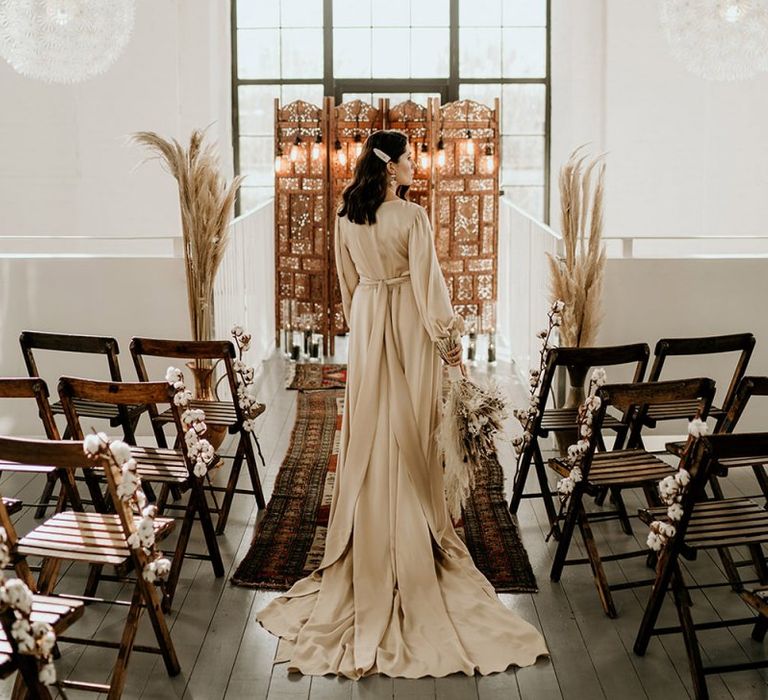 Bride in Satin Wedding Dress Standing in Front of a Moroccan Screen and Rug