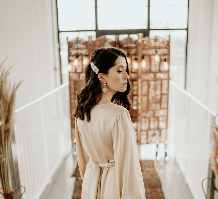 Stylish Bride in Satin Wedding Dress and Peal Hair Slide Standing in Front of a Moroccan Screen and Rug