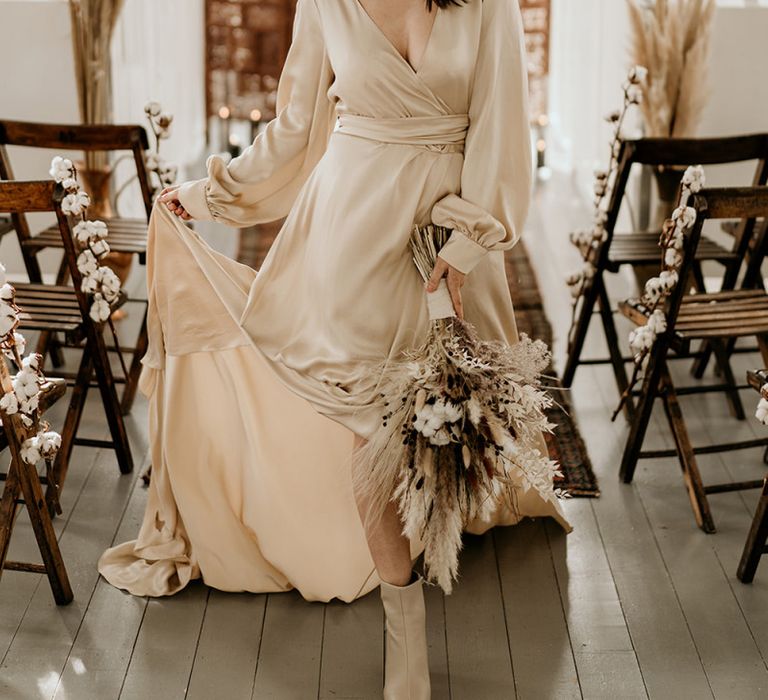 Stylish Bride in Satin Wedding Dress and Bridal Boots Holding a Dried Flower Wedding Bouquet