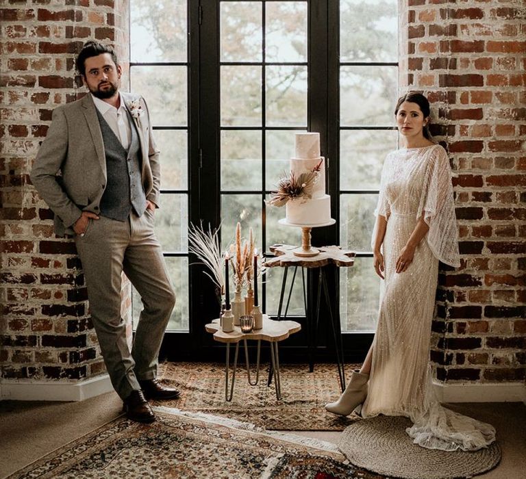 Bride in Sequin Wedding Dress and Groom in Wool Suit with Top Knot Standing by the Wedding Cake Display