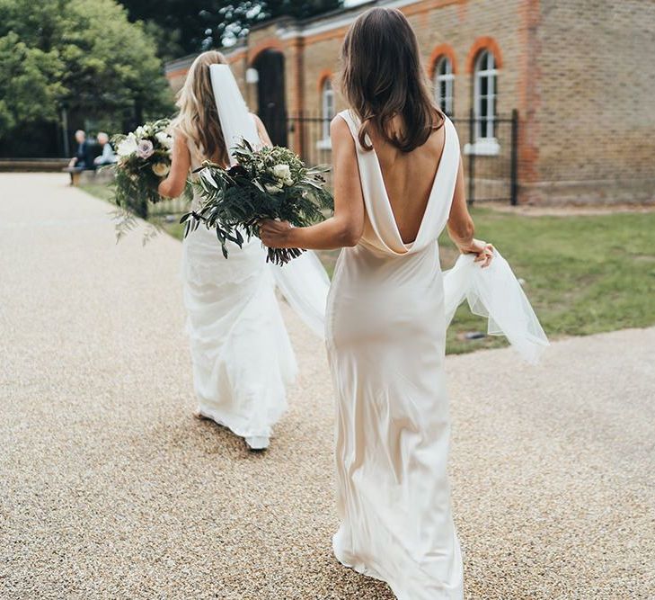 Bridesmaid Assisting Bride on Way to Ceremony in Cream Bridesmaid Dress