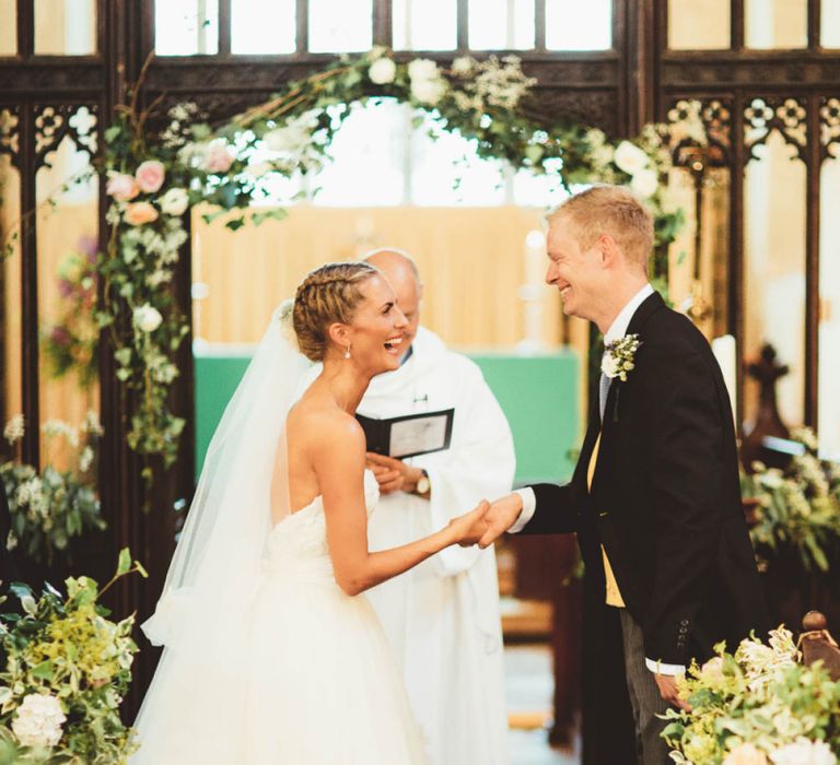 Bride in Tulle and Applique Wedding Dress and Groom in Traditional Morning Suit Exchanging Wedding Vows at the Altar