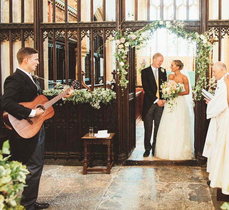 Bride and Groom Standing at the Altar with Church Wedding Flowers