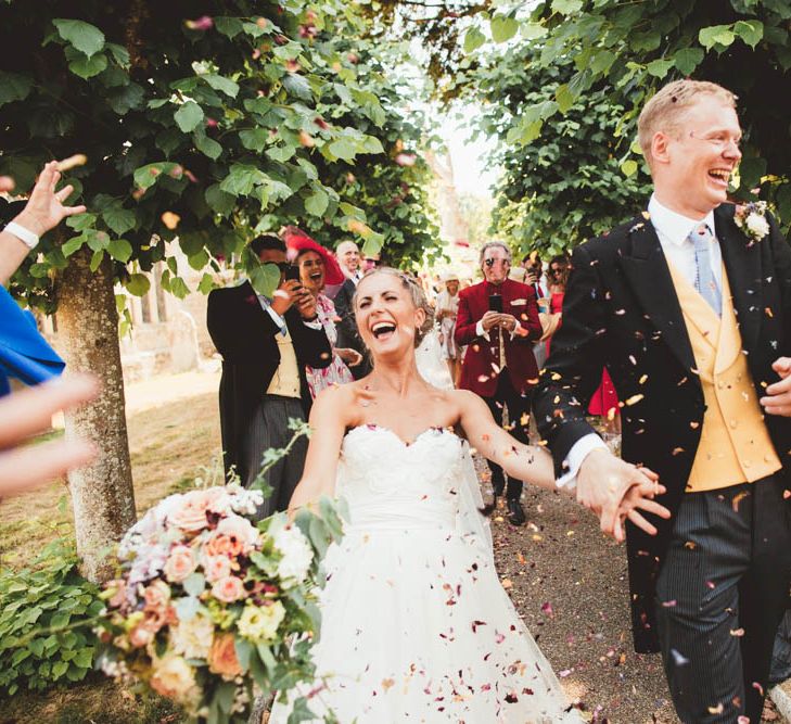 Confetti Exit with Bride in Halfpenny London Wedding Dress Holding a Blush, White and Green Bouquet and Groom in Traditional Morning Suit