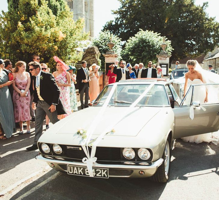 Groom Helping His Bride into their Vintage Wedding Car