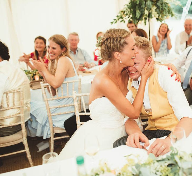 Bride in Tulle and Applique Halfpenny London Wedding Dress with Groom in Yellow Waistcoat Laughing and Joking During Marquee Wedding Reception