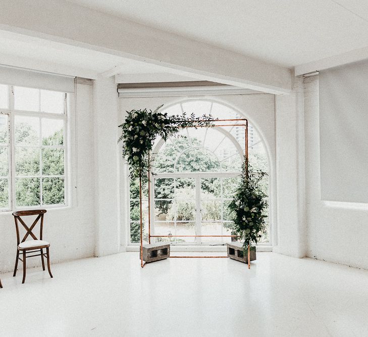 Wedding Ceremony Decor | Copper Arch with White Flowers and Foliage | Whitewashed Walls | Same Sex Wedding with Industrial Styling at Wimborne House | Marmelo Photography