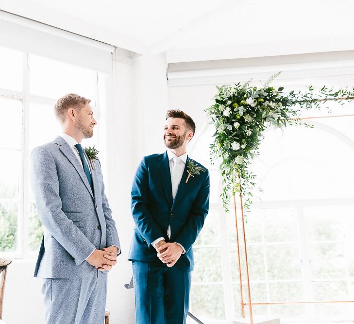 Wedding Ceremony | Groom in Dark Petrol Blue Suit by Paul Smith | Groom in Light Blue Made-To-Measure Suit by Beggars Run | Copper Arch with White Flowers and Foliage | Same Sex Wedding with Industrial Styling at Wimborne House | Marmelo Photography