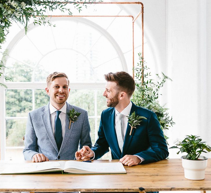 Signing of Register | Copper Arch with White Flowers and Foliage | Groom in Dark Petrol Blue Suit by Paul Smith | Groom in Light Blue Made-To-Measure Suit by Beggars Run | Same Sex Wedding with Industrial Styling at Wimborne House | Marmelo Photography