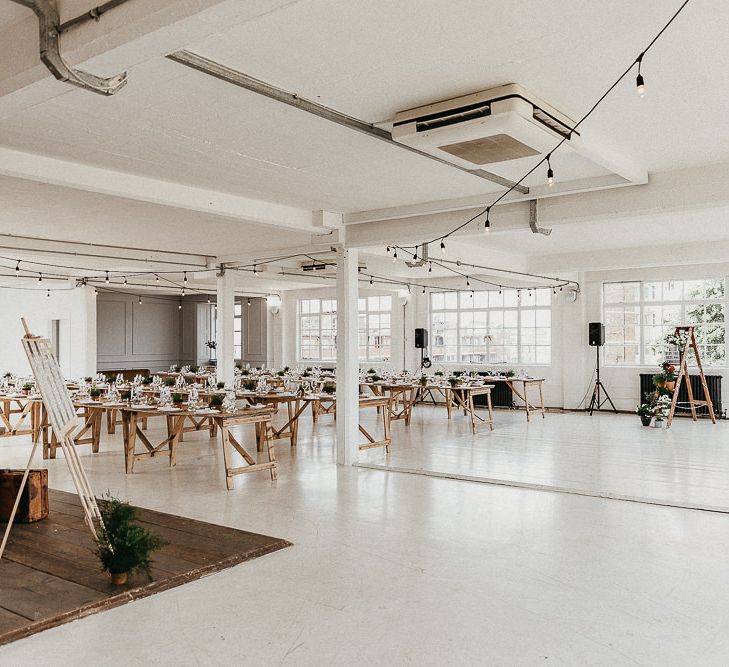 Wedding Reception Decor | Trestle Tables | Festoon Lights | Seating Plan | Windows | Whitewashed Walls | Industrial Ladder with Potted Plants | Same Sex Wedding with Industrial Styling at Wimborne House | Marmelo Photography