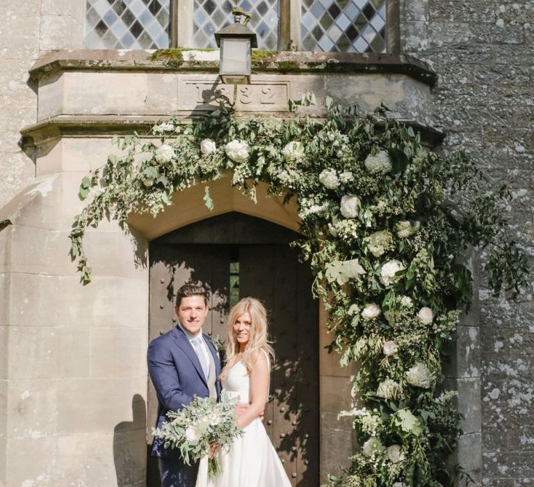 Bride and groom portrait outside the church under floral arch