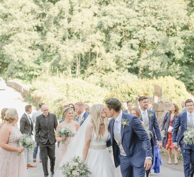 Bride and groom kissing in the church courtyard