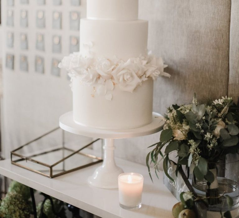 Elegant white wedding cake with wax seal escort card backdrop