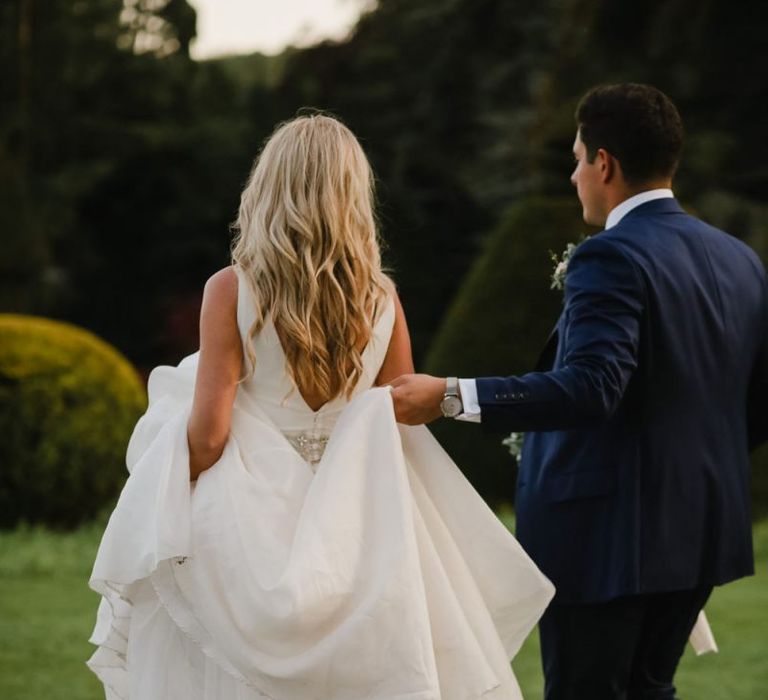 Groom helping his bride with her Sassi Holford wedding dress