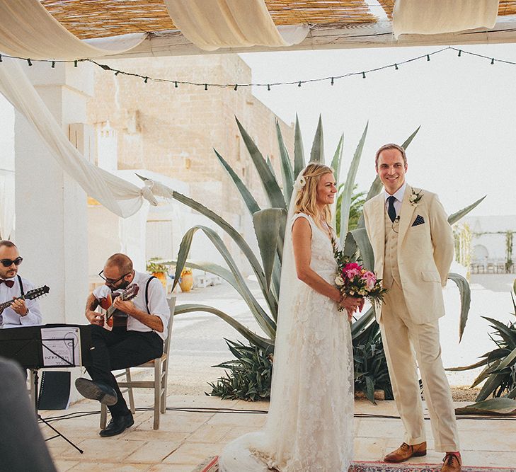 Outdoor Wedding Ceremony | Bride in Custom Clemence Halfpenny London Bridal Gown | Groom in Cream Three Piece Suit | Brightly Coloured Destination Wedding at Masseria Potenti Wedding Venue, Puglia, South Italy | Petar Jurica Photography | Marco Odorino Film