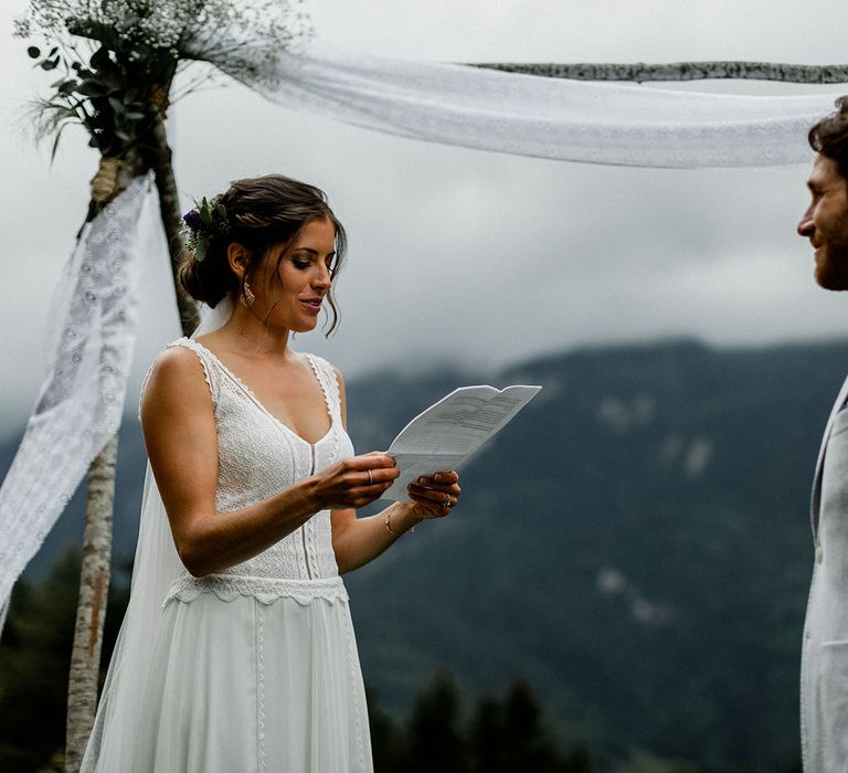 Bride in Mariées Passion Wedding Dress and Groom in Grey Blazer Saying Their Wedding Vows