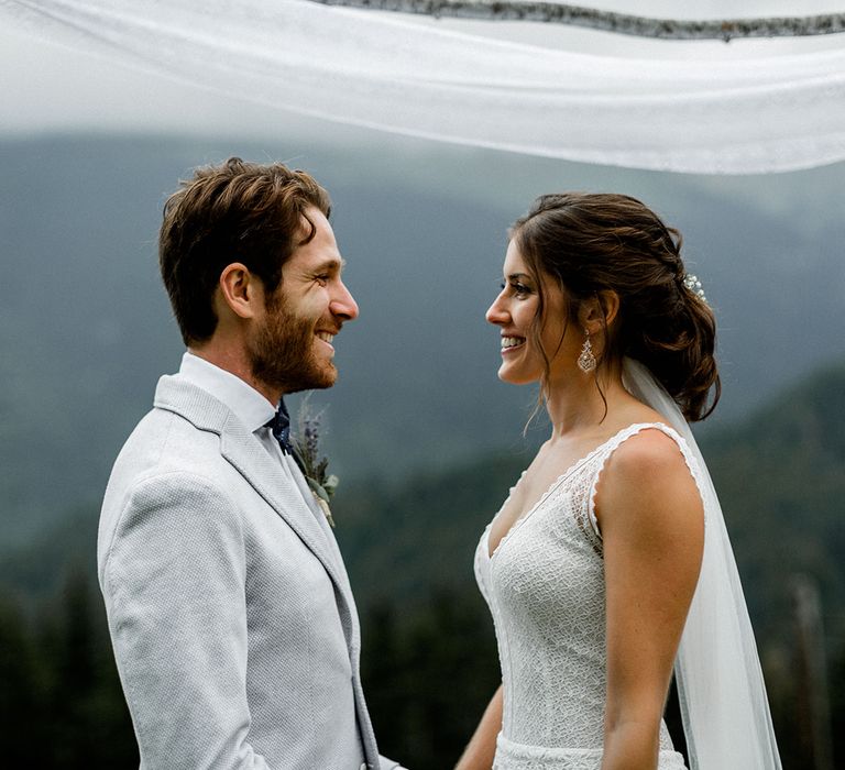 Bride in Mariées Passion Wedding Dress and Groom in Grey Blazer Holding Hands