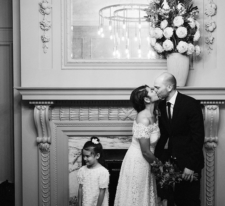 Bride in Lace Whistles Wedding Dress with High/Low Hem and Bardot Neckline | Groom in Black Reiss Jacket and Black Nudie Jeans with Church's Shoes | Flower Girl in White Zara Dress with Short Sleeves and Scoop Back | Wedding Ceremony at Old Marylebone Town Hall | High Street Wedding Dress for an Intimate Crouch End Pub Wedding with Bright Flowers | Miss Gen Photography