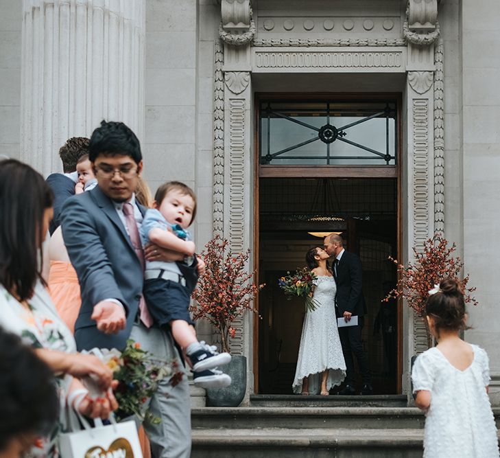 Bride in Lace Whistles Wedding Dress with High/Low Hem and Bardot Neckline | Silver Sparkly Kurt Geiger Heels | Groom in Black Reiss Jacket and Black Nudie Jeans with Church's Shoes | Bridal Bouquet with Bright Wild Flowers | Wedding Ceremony at Old Marylebone Town Hall | High Street Wedding Dress for an Intimate Crouch End Pub Wedding with Bright Flowers | Miss Gen Photography