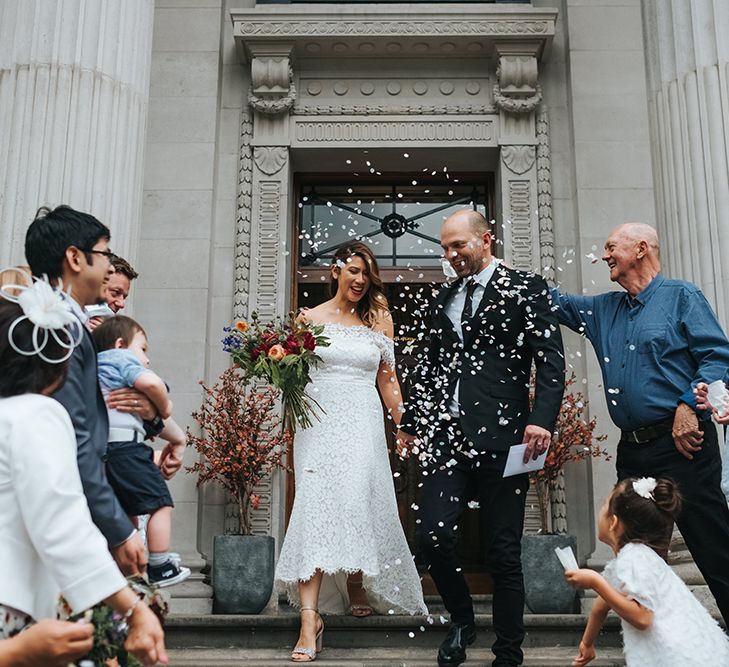 Bride in Lace Whistles Wedding Dress with High/Low Hem and Bardot Neckline | Silver Sparkly Kurt Geiger Heels | Groom in Black Reiss Jacket and Black Nudie Jeans with Church's Shoes | Bridal Bouquet with Bright Wild Flowers | Wedding Ceremony at Old Marylebone Town Hall | High Street Wedding Dress for an Intimate Crouch End Pub Wedding with Bright Flowers | Miss Gen Photography