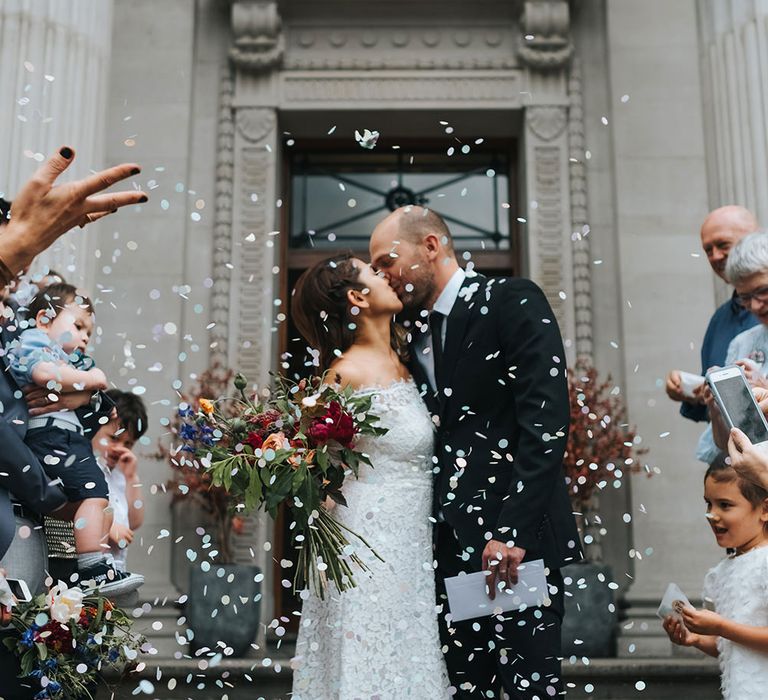 Bride in Lace Whistles Wedding Dress with High/Low Hem and Bardot Neckline | Silver Sparkly Kurt Geiger Heels | Groom in Black Reiss Jacket and Black Nudie Jeans with Church's Shoes | Bridal Bouquet with Bright Wild Flowers | Wedding Ceremony at Old Marylebone Town Hall | High Street Wedding Dress for an Intimate Crouch End Pub Wedding with Bright Flowers | Miss Gen Photography