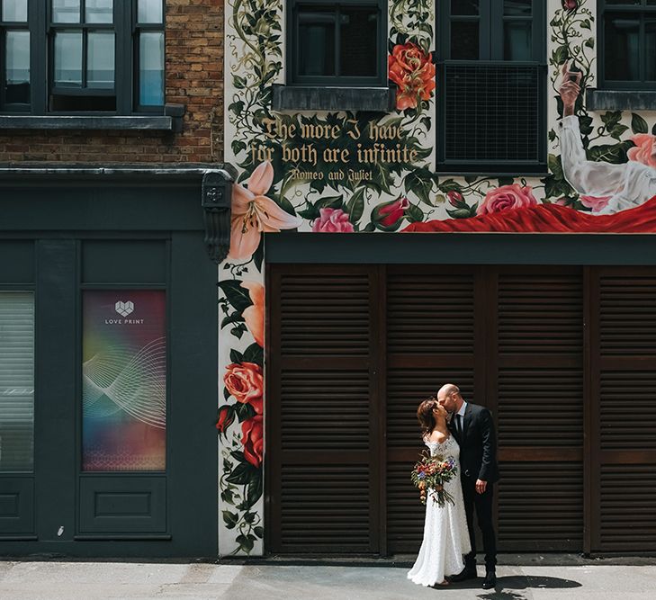 Bride in Lace Whistles Wedding Dress with High/Low Hem and Bardot Neckline | Silver Sparkly Kurt Geiger Heels | Groom in Black Reiss Jacket and Black Nudie Jeans with Church's Shoes | Bridal Bouquet with Bright Wild Flowers | High Street Wedding Dress for an Intimate Crouch End Pub Wedding with Bright Flowers | Miss Gen Photography