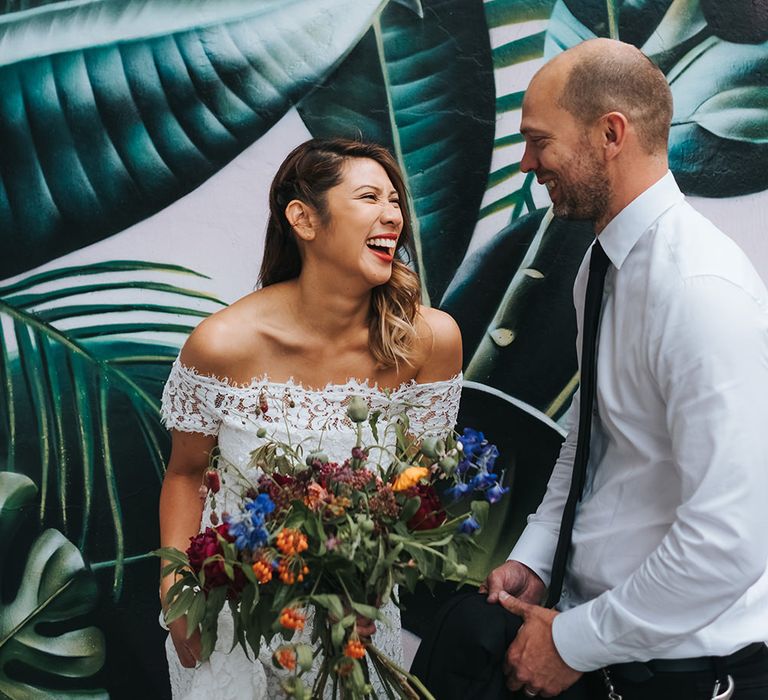 Bride in Lace Whistles Wedding Dress with High/Low Hem and Bardot Neckline | Groom in Black Reiss Jacket and Black Nudie Jeans with Church's Shoes | Bridal Bouquet with Bright Wild Flowers | High Street Wedding Dress for an Intimate Crouch End Pub Wedding with Bright Flowers | Miss Gen Photography