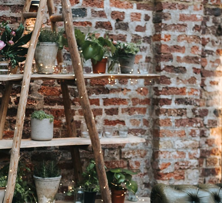 Wooden Retro Ladder Shelving Display with Pot Plants and Fairy Lights | Succulents in Initial Shaped Vases | Leather Sofas | Victoria Stakes Pub Wedding Reception | High Street Wedding Dress for an Intimate Crouch End Pub Wedding with Bright Flowers | Miss Gen Photography