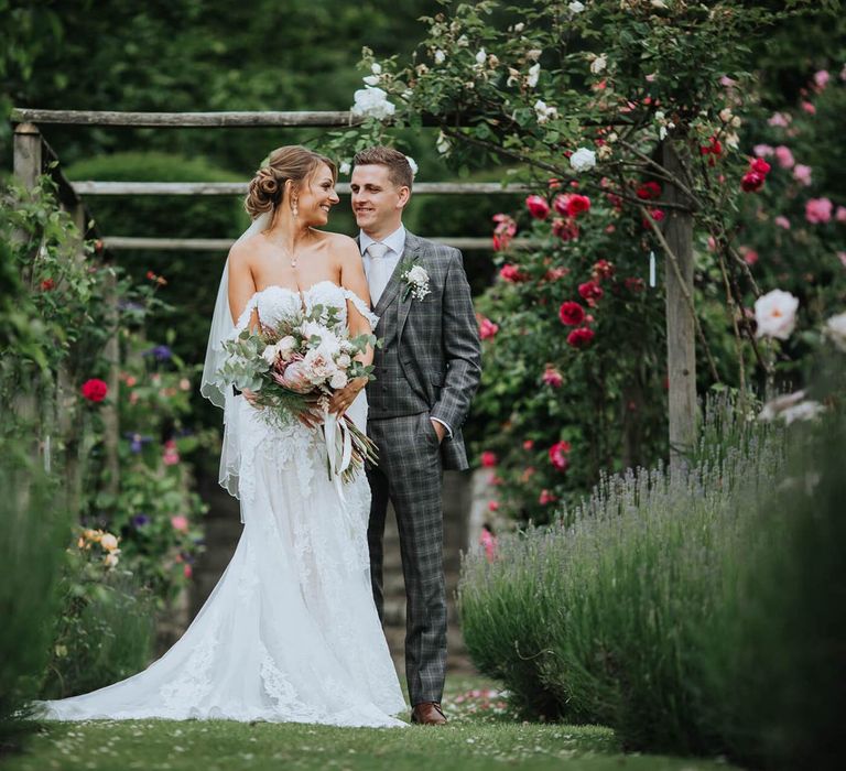 Bride and Groom Embrace Under Floral Backdrop