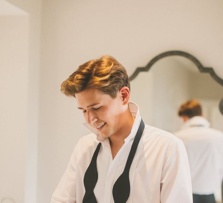 Groom Getting Ready on the Wedding Morning with a Loose Bow Tie Around His Neck