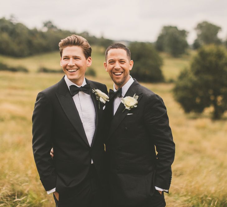 Portrait of Same Sex Couple in Black Tie Suits Smiling in a Field