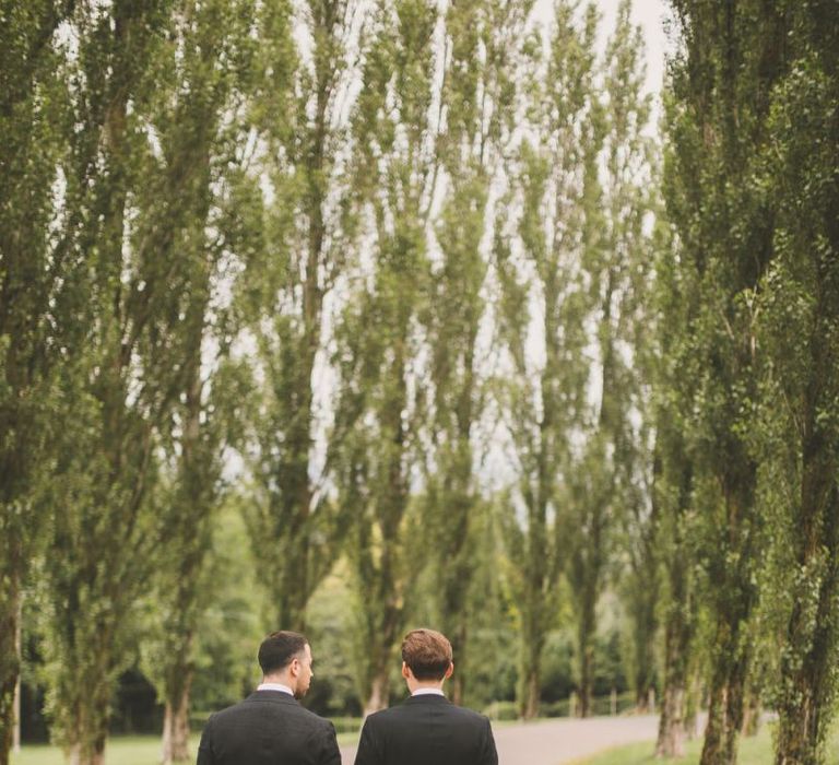 Portrait of Same Sex Couple in Black Tie Suits Holding Hands Walking Down a Country Lane