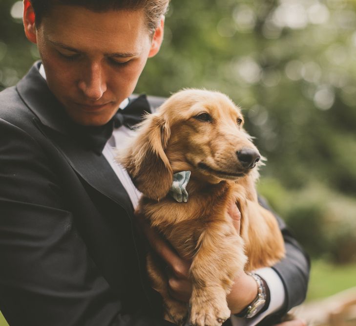 Groom in Tuxedo Holding His Pet Long-Haired Dachshund